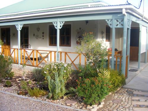 a front porch of a house with flowers and plants at Karoo Chat in Prince Albert