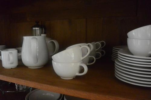 a shelf with white cups and plates on it at Wiehen Inn in Heddinghausen