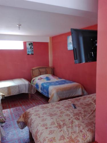 a room with two beds and a flat screen tv at Hostal Puerto Alegre in Copacabana