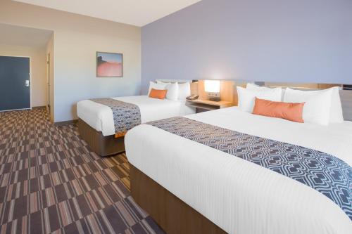 a hotel room with two beds and a flat screen tv at Microtel Inn & Suites by Wyndham Cuauhtemoc Campos Menonitas in Cuauhtémoc