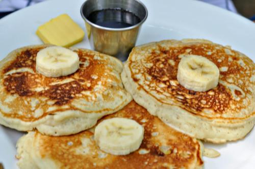three pancakes with bananas and butter on a white plate at Pacheco Tours Beach Cabins in Drake
