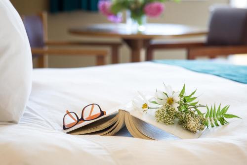 a pair of glasses and a book on a bed at The Lodge at Arrow Lakes in Nakusp