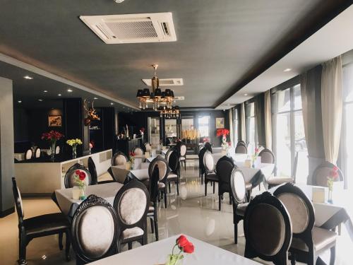 uma sala de jantar com mesas e cadeiras brancas em Taris Art Hotel Phrae em Phrae