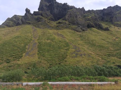 a grassy hill with a mountain in the background at Welcome Holiday Home in Eyvindarhólar