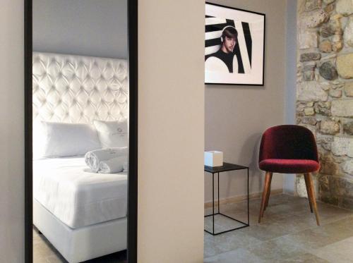a mirror in a room with a bed and a chair at CinqueSuites Ortigia in Siracusa
