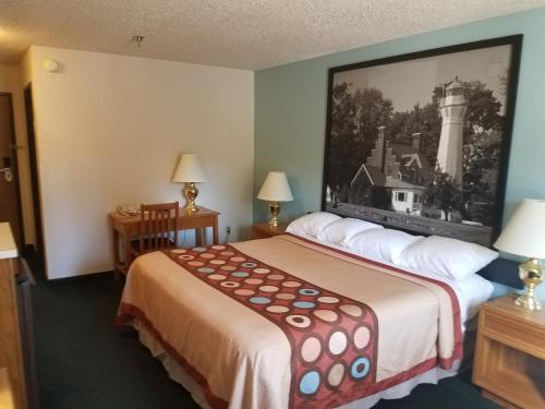 a hotel room with a bed and a picture on the wall at Super 8 by Wyndham Houghton Lake in Houghton Lake