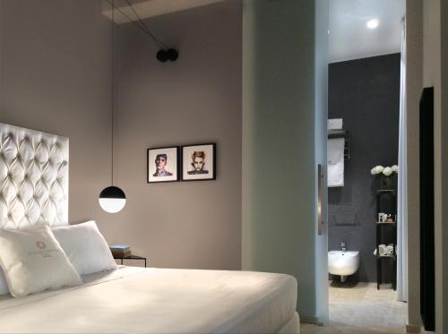 a bedroom with a bed and a bathroom with a sink at CinqueSuites Ortigia in Siracusa