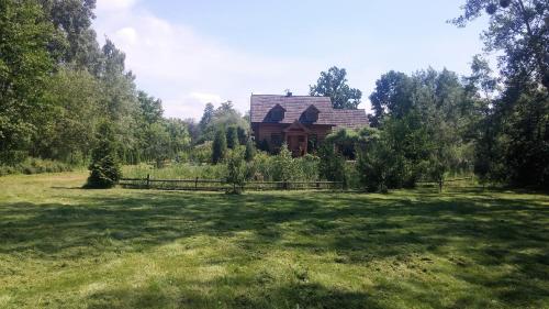 a house in the middle of a field with a fence at Dom Wilków in Leoncin