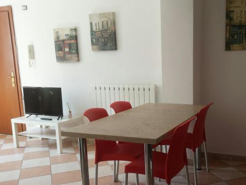 a dining room table with red chairs and a television at Residence Shopping Outlet in Novi Ligure