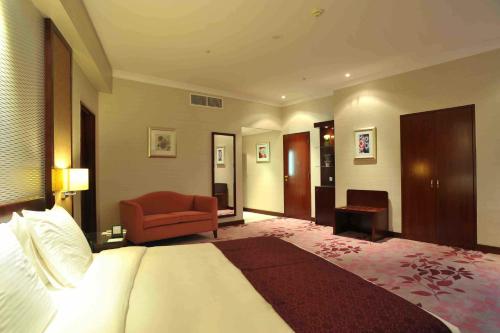 a hotel room with a bed and a red chair at Al Marwa Rayhaan by Rotana - Makkah in Makkah