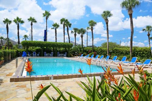 a pool with lounge chairs and palm trees at La Fiesta Ocean Inn & Suites in Saint Augustine Beach