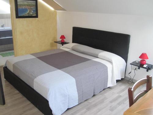 トリノにあるLa Mansarda di Legnoのベッドルーム1室(大型ベッド1台、テーブル2台、ランプ2つ付)