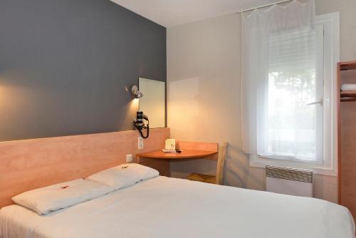 a bedroom with a white bed and a small table at KYRIAD DIRECT Orleans - La Chapelle St Mesmin in La Chapelle-Saint-Mesmin