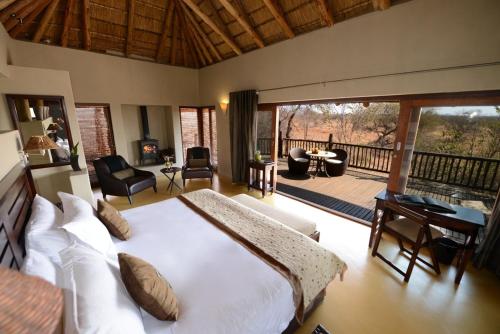 a bedroom with a large bed and a balcony at Etali Safari Lodge in Madikwe Game Reserve