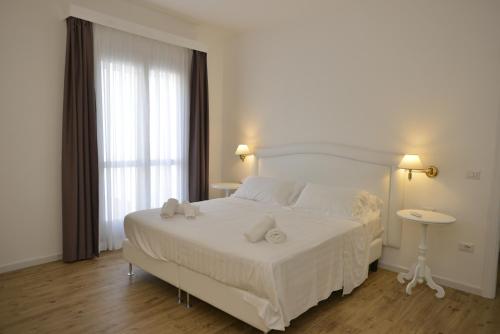 a bedroom with a white bed and a table at Arenosu Comfort Country Guesthouse in Fertilia