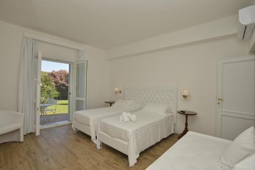 a white bedroom with two beds and a balcony at Arenosu Comfort Country Guesthouse in Fertilia