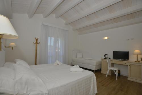 a white bedroom with a bed and a desk with a computer at Arenosu Comfort Country Guesthouse in Fertilia
