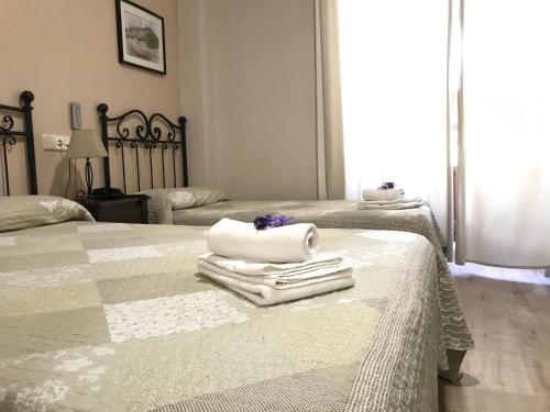 two beds with towels on them in a bedroom at Hostal El Pilar in Madrid