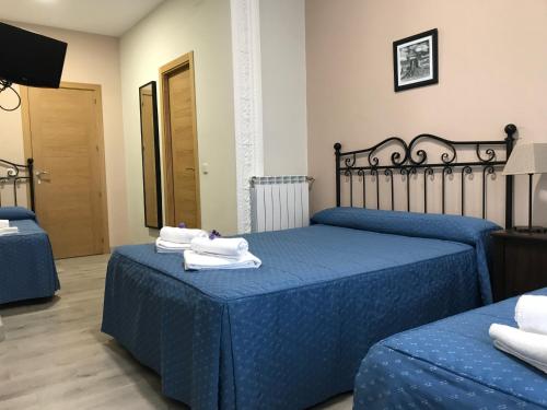 a bedroom with two beds with blue sheets and towels at Hostal El Pilar in Madrid