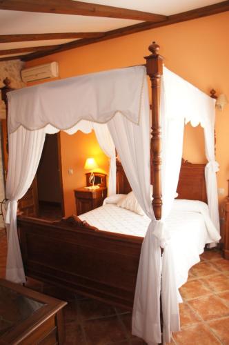 a bedroom with a canopy bed with white curtains at Casa Rural Blas in Brihuega