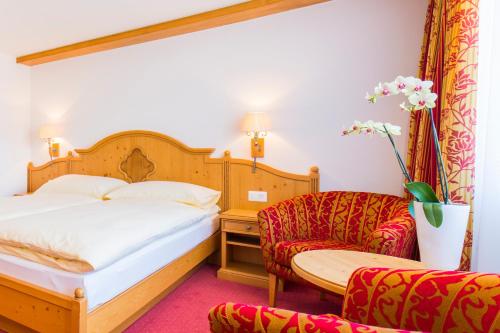 Habitación de hotel con cama y silla en Hotel Excelsior en Zermatt