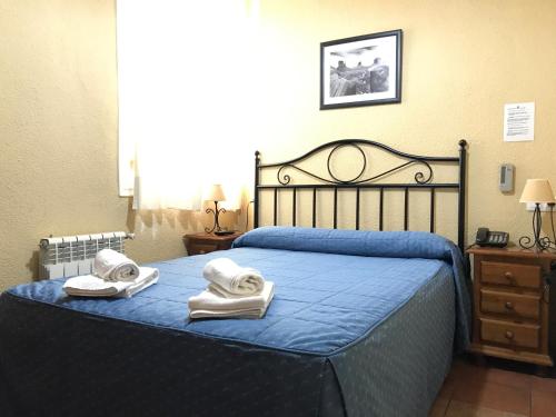 a bedroom with a blue bed with towels on it at Hostal El Pilar in Madrid