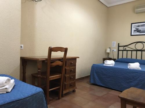 a room with two beds and a desk and a chair at Hostal El Pilar in Madrid