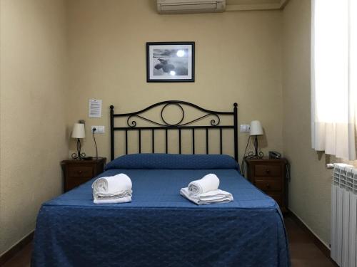 a bedroom with a blue bed with two towels on it at Hostal El Pilar in Madrid