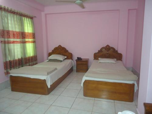 zwei Betten in einem Zimmer mit rosa Wänden in der Unterkunft Hotel Green Castle in Rangamati