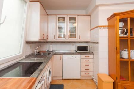 uma cozinha com armários brancos e um lavatório em Iteiko Enea em Zarautz