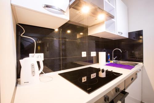 Apartman Vita في زغرب: مطبخ مع دواليب بيضاء ومغسلة