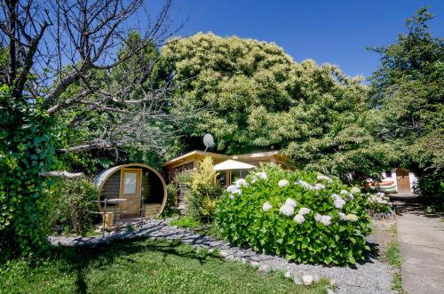 una casa con un jardín con flores en el patio en Chili Kiwi Lakefront Backpackers, en Pucón