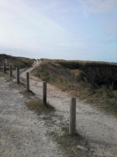 a dirt road with wooden posts on the side at les roches du Cabellou 150M de la mer in Concarneau