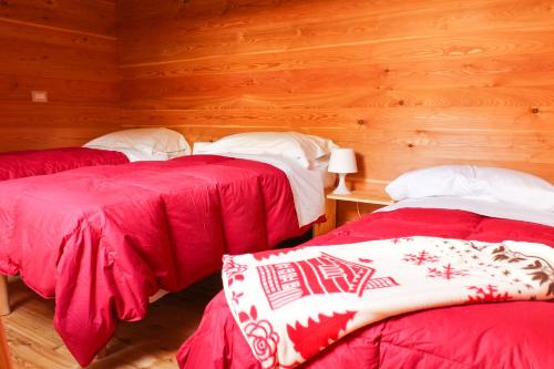 a room with two beds with red and white sheets at Agriturismo Alagna in Alagna Valsesia