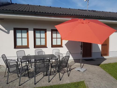 a table and chairs with a red umbrella in front of a house at Lipnoapartments 88 in Lipno nad Vltavou