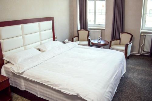 a bedroom with a large white bed and two chairs at Hotel MUSE in Sankt Pölten