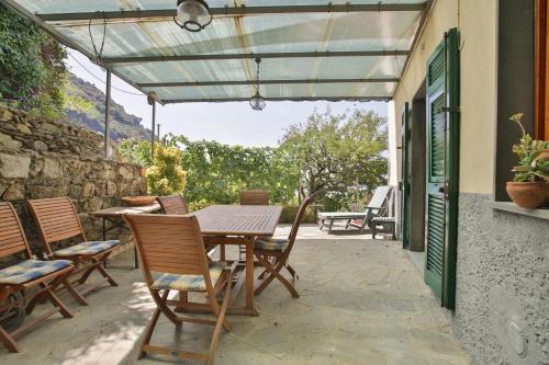 un patio con mesa, sillas y pared de piedra. en 5 Terre For You en Riomaggiore
