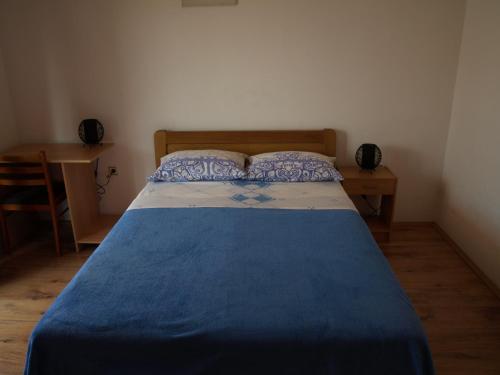 a bedroom with a bed with a blue blanket and a desk at Apartmani Adriana1979 in Vodice