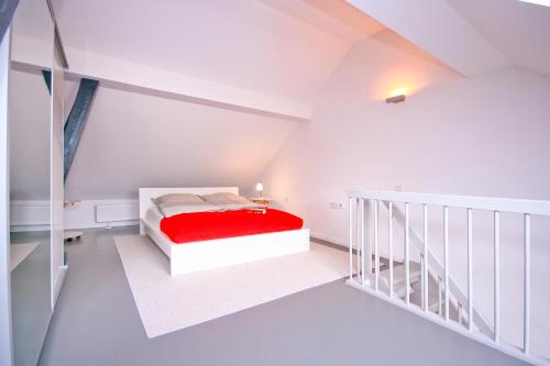 Dormitorio blanco con cama roja en el ático en Haus Dohrmann, en Binz