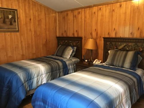 two beds in a room with wooden walls at Big Cypress in Lake Panasoffkee