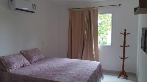 1 dormitorio con cama y ventana en Vila Verona en Praia do Forte