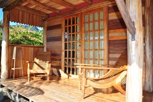 eine Veranda einer Holzhütte mit Schaukelstühlen in der Unterkunft Kopal in Baeza