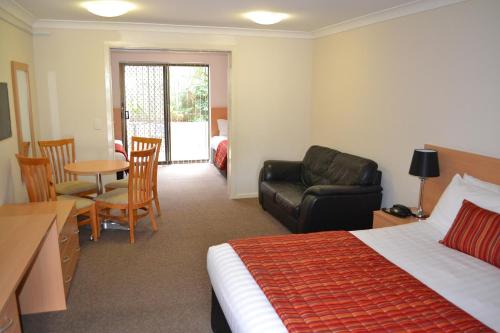a hotel room with a bed and a couch and a table at Comfort Inn Grammar View in Toowoomba