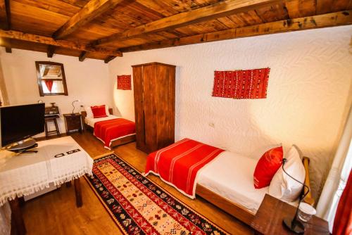 a room with two beds and a desk and a television at Hotel Tradita in Shkodër