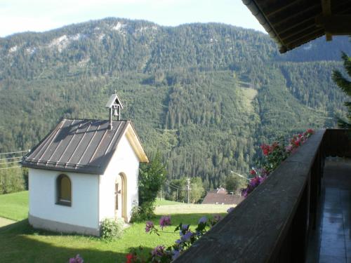 a small chapel on a lawn with mountains in the background at Bichlhof Riedenberg in Thiersee