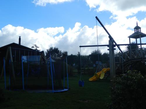 a playground with a swing set and a clock tower at Cabañas Lomas del Lago in Frutillar