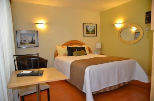 a hotel room with a bed and a table at Motel Derfal in Repentigny