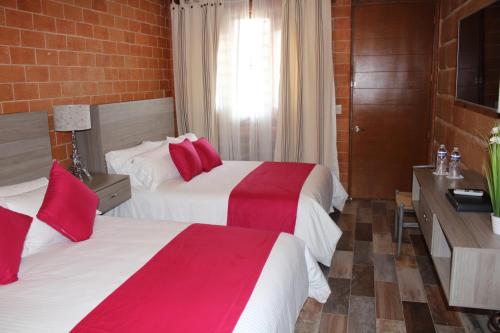 a hotel room with two beds with red pillows at Hotel Boutique La Herencia in Tequisquiapan