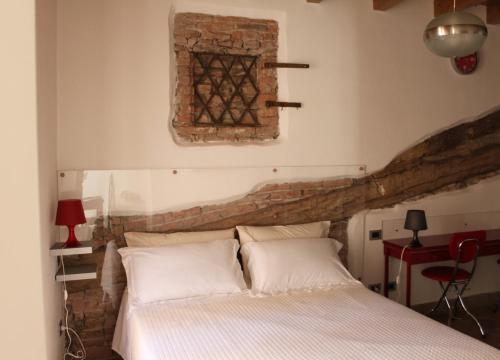 1 dormitorio con cama y pared de ladrillo en La Filanda, en Brescia