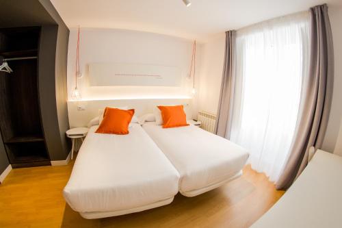 two beds in a room with two orange pillows at Apartamento SoMbrereria RiMboMbin in Burgos